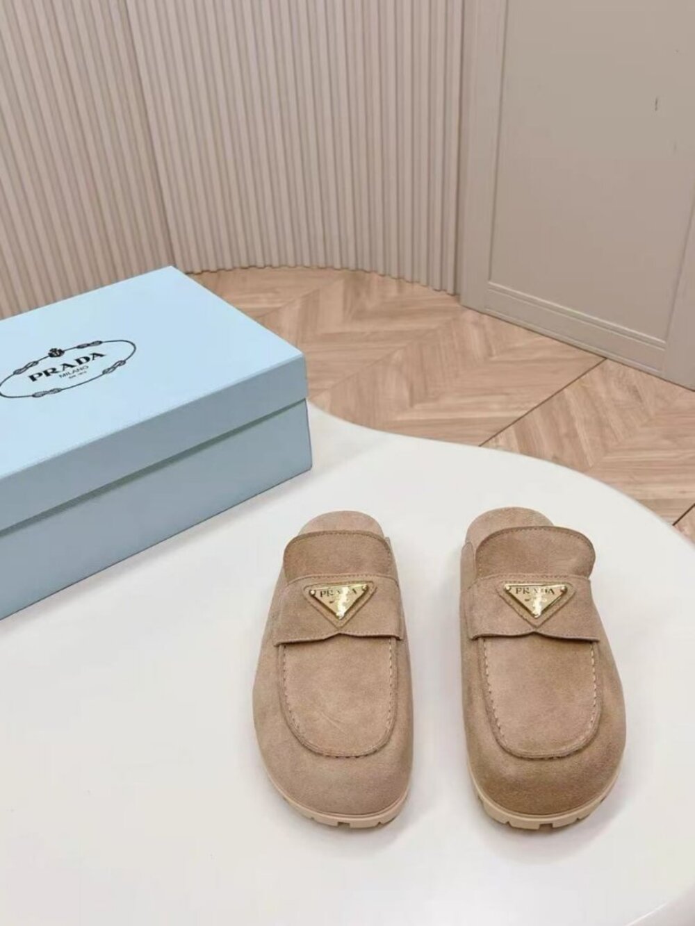 Prada beige slip‑on mules with triangular logo badge